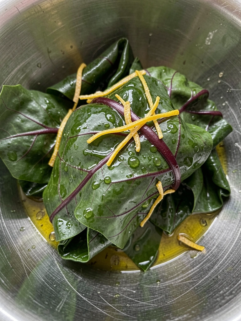 Ingredientes sobre tábua de madeira: acelga, alho, cebola, shoyu e azeite.